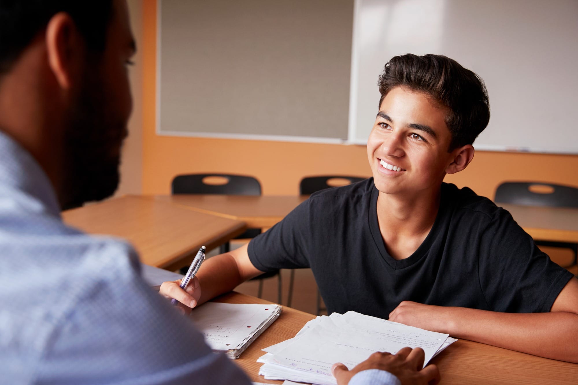 High School Tutor Giving Male Student One to One Tuition at Desk.