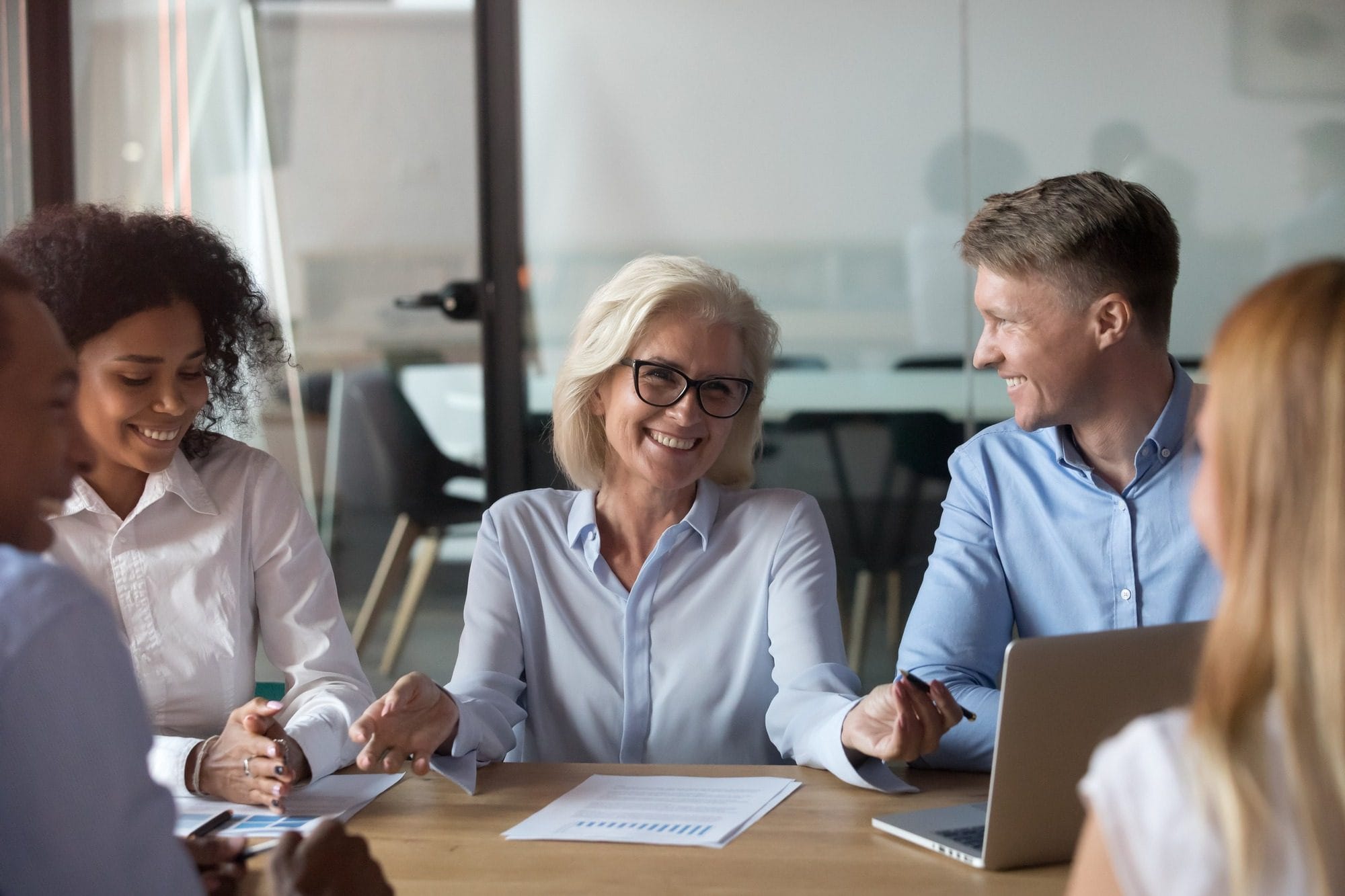 Different People Young and Aged Multinational Employees Sitting Around Table in Conference Modern Room Discussing Further Cooperation or Studying With Middle Aged Instructor Experienced Business Coach